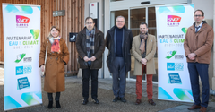 1 femme et 4 hommes devant les panneaux de signature du contrat 